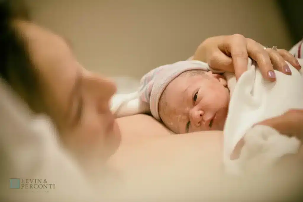 Mother holding a newborn infant against her chest in the hospital