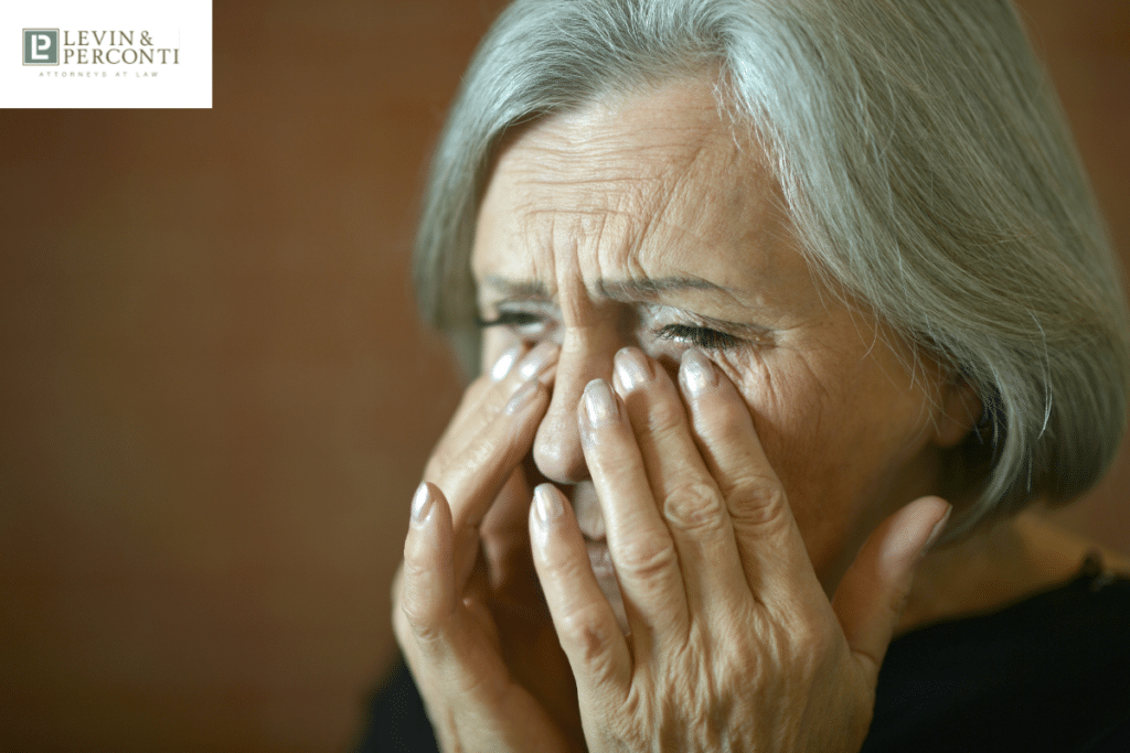 An older lady sobs with her hands covering her face.