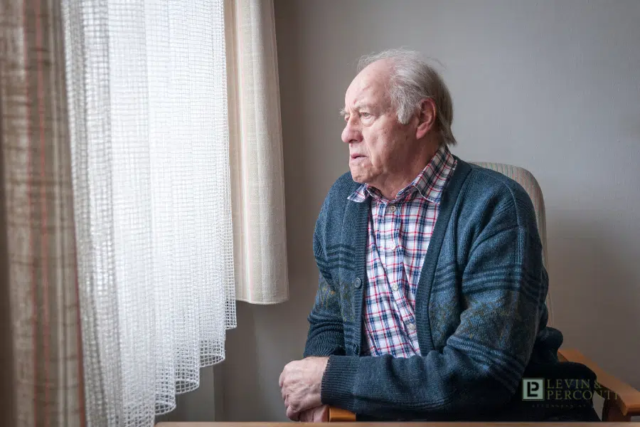 elderly man looking out a nursing home window