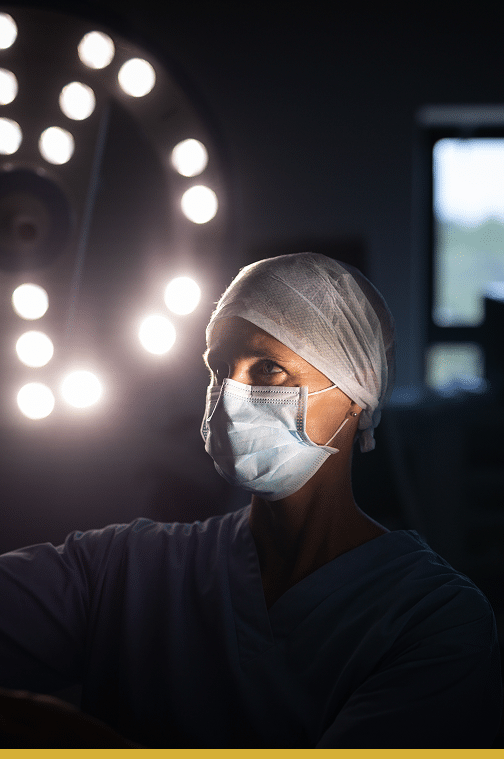 Doctor or nurse reviewing an x-ray in a dark room, there are lights behind her